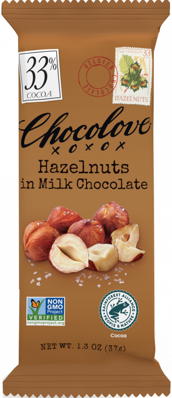 A Chocolove Hazelnuts in Milk Chocolate mini bar is in its sealed packaging. The wrapper is a warm brown color with black elegant script branding. An image of whole and halved hazelnuts with salt crystals is prominently displayed. A 33% cocoa label is in the top left corner, and a stamp-style hazelnut illustration with a red Belgian Chocolate seal is near the top. Certification logos for Non-GMO and Rainforest Alliance are at the bottom.