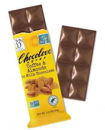A Chocolove Toffee & Almonds in Milk Chocolate bar is partially unwrapped, revealing smooth milk chocolate squares with embossed heart designs. The bright yellow wrapper has a vintage-inspired design, featuring an image of golden, crunchy toffee pieces and whole almonds. A 33% cocoa label is displayed in the top left corner, and a stamp-style illustration of a chocolatier stirring toffee is near the top. The glossy chocolate squares showcase the rich, Belgian milk chocolate quality.