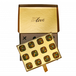 Open Chocolove Dubai Style Pistachio & Kadayif Milk Chocolate Gift Box with gold inner lid reading “Share it with someone you love” and tray of 12 decorated chocolates.