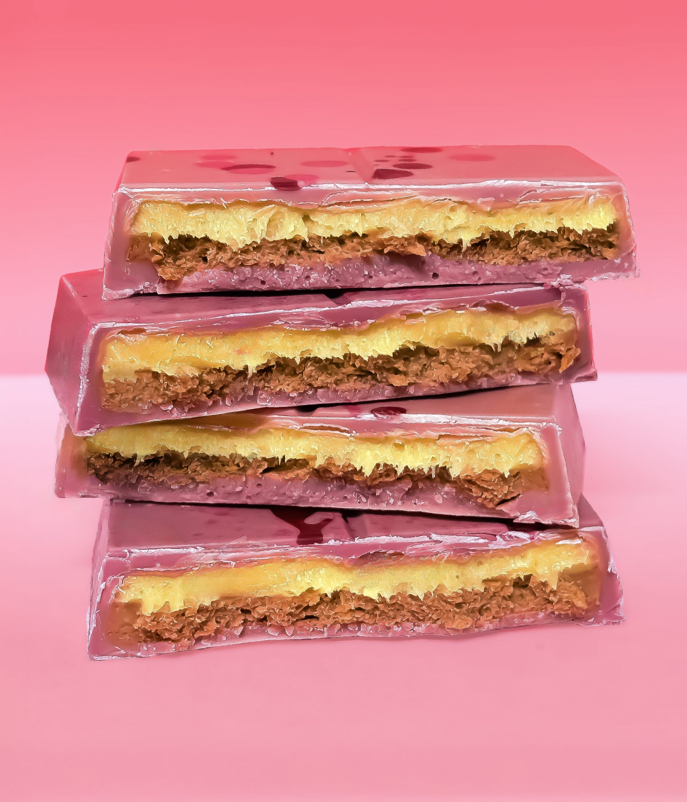 Stacked Chocolove Sunburst Ruby Chocolate Luxe Bars showing layers of mango-passion fruit filling, hazelnut, and crisp feuilletine.